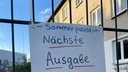 An einem Metallzaun hängt ein weißes Schild mit der Aufschrift: "- Sommerpause - Nächste Ausgabe"