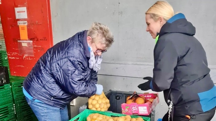 Zwei Frauen beugen sich über Kisten mit Gemüse