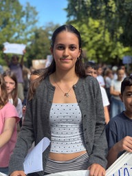 Schülerin steht mit einem Transparent in der Hand in der ersten Reihe eines Demonstrationszuges
