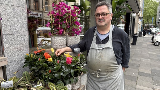 ein Mann (Bernd Steiner) steht neben einem Strauß Blumen vor dem Blumenladen Steiner.