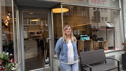eine Frau (Kerstin Seybold) mit einer blauen Jeansjacke steht vor dem Friseursalon Küpper Seybold.