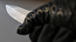 Jeman hält mit einem schwarzem Handschuh ein Messer mit einer silbernen, langen Klinge. 