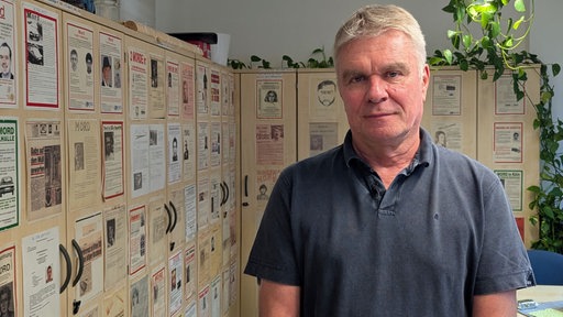 Markus Weber steht in seinem Büro vor alten Fahndungsplakaten