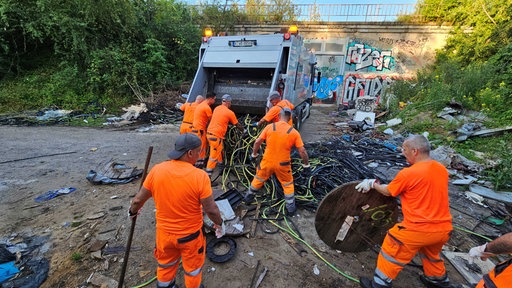 Arbeiter der Abfallwirtschaftsbetriebe entsorgen Müll in einen Müllwagen