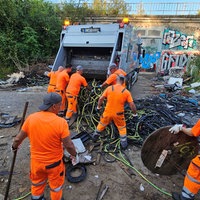 Arbeiter der Abfallwirtschaftsbetriebe entsorgen Müll in einen Müllwagen