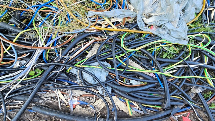 Auf einem Feldweg liegen haufenweise Hüllen von Elektrokabeln