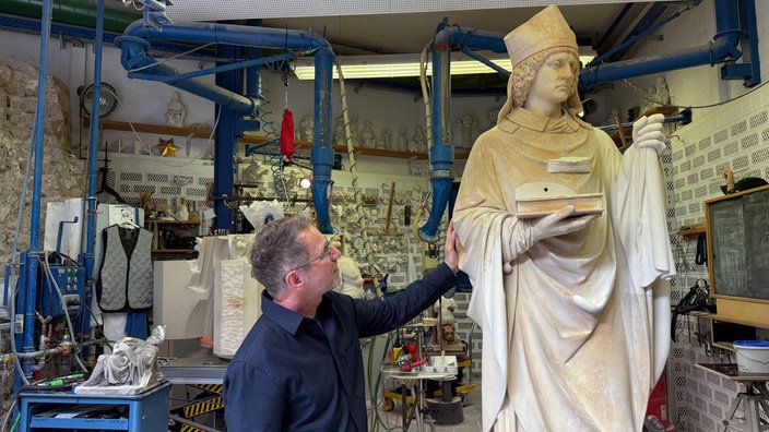 Dombaumeister Peter Füssenich schaut sich eine Skulptur vom heiligen Alban von Mainz an.