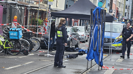 Abgesperrter Straßenbereich mit Polizeikräften und einem Pavillon neben Fahrzeugen und Fahrrädern.