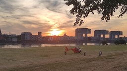 Ein Rettungshubschrauber steht auf den Poller Wiesen, im Hintergrund die Kranhäuser.