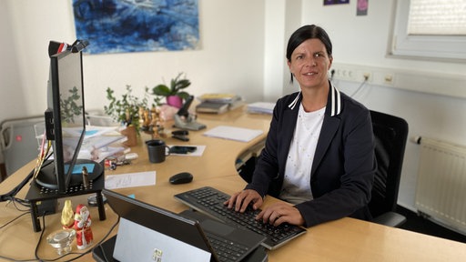 Sarah Primus sitzt in einem Büro am Schreibtisch