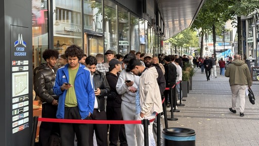 Viele Menschen stehen vor Nhas City Chicken auf der Breite Straße 