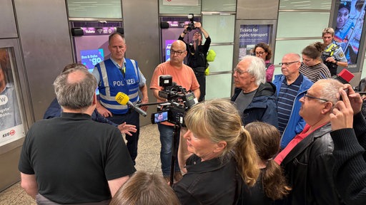 Menschengruppe steht im Kölner Hauptbahnhof um Polizisten herum 