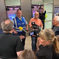 Menschengruppe steht im Kölner Hauptbahnhof um Polizisten herum 