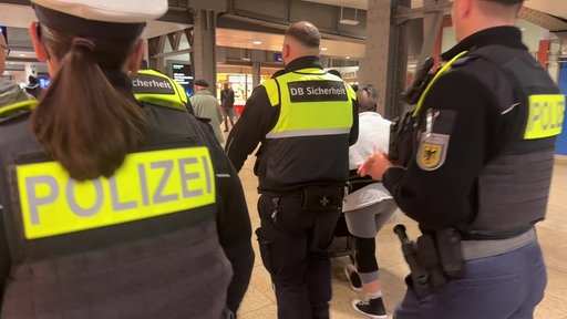 Beamte von DB Sicherheit und Polizei mit gelben Schutzwesten auf Streife im Kölner Hauptbahnhof