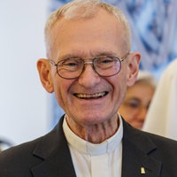 Franz Meurer lächelt in die Kamera. Im Hintergrund sind weitere Menschen.