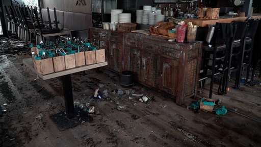 Im Gastraum des Restaurants liegen Glasscherben auf dem Boden. Teile der Decke sind auf die Stühle und Bänke gefallen.