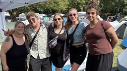 Gruppe von jungen Menschen auf dem Festivalgelände lächeln