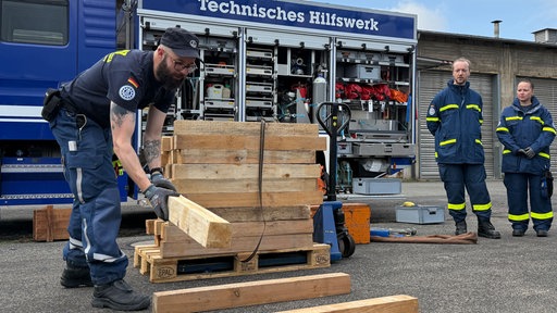 Ein Mann stapelt Holzblöcke zu einem Kreuzholzstapel.