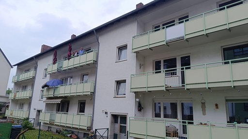 Fassade eines Mehrfamilienhauses. Auf dem Balkon oben links stehen drei Frauen.