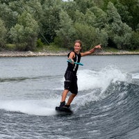 Mann der auf einem Wakebaord steht und dabei ein Schnur hält.