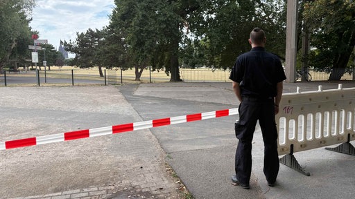 Ein Mitarbeiter des Ordnungsamtes steht hinter Absperrband.