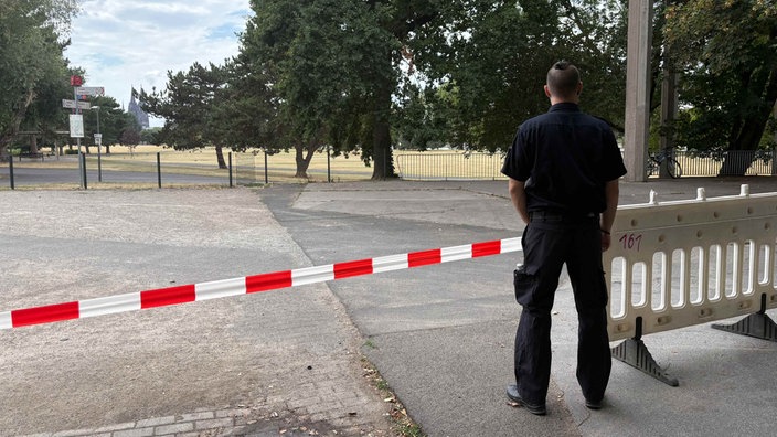 Ein Mitarbeiter des Ordnungsamtes steht hinter Absperrband.