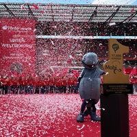Konfetti fliegt durch die Luft im Rhein-Energie-Stadion. Im Vordergrund ein Preis mit der Aufschrift 17 000 Kinder und ein Maskottchen daneben. Im Hintergrund viele Kinder.