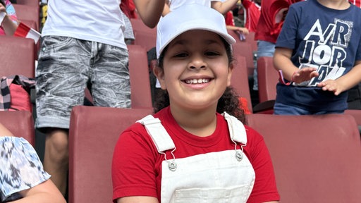 9-jährige Schülerin Anissa sitzt im Rhein-Energie-Stadion, lächelt in die Kamera.