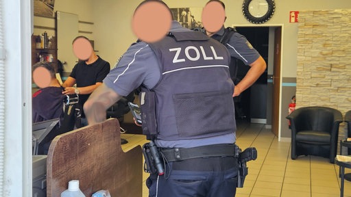 Zwei Zollbeamte kontrollieren einen Barbershop