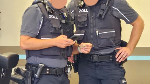 Zwei Zollbeamte kontrollieren einen Personalausweis