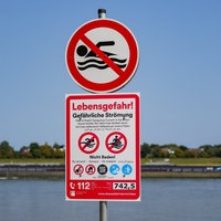 Schilder, die auf die Gefahren beim Schwimmen im Rhein hinweisen