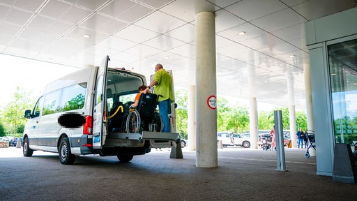 Eine Frau im Rollstuhl verlässt das Taxi.