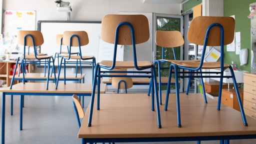Stühle stehen in einer Schule auf den Tischen.