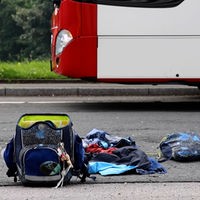 Schulrucksack auf der Straße vor einem Bus