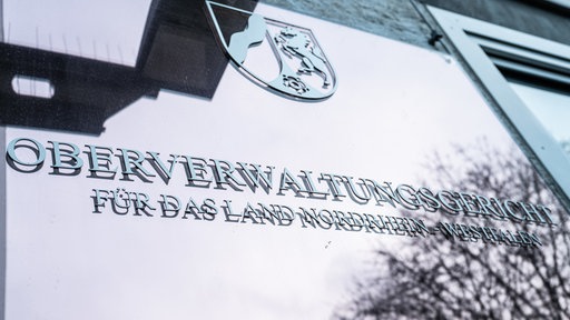 Fensterscheibe mit dem Schriftzug "Oberverwaltungsgericht für das Land Nordrhein-Westfalen" und dem Wappen von NRW.