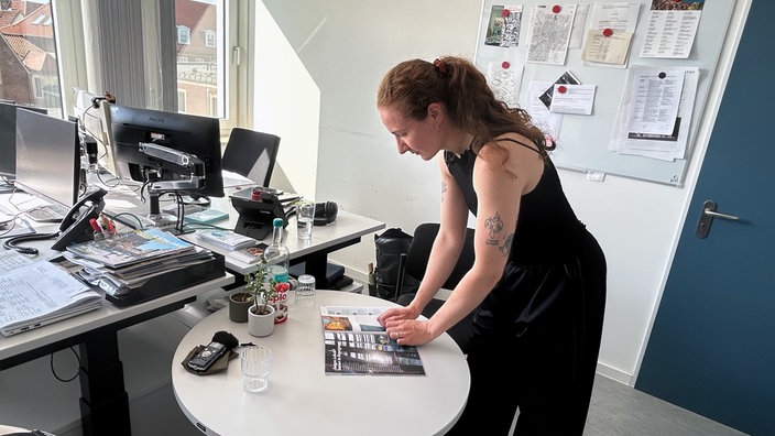 Eine Frau schaut sich im Büro ein Prospekt an.