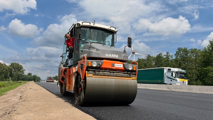 Ein Bauarbeiter fährt eine Walze bei den Asphaltarbeiten auf der A1.