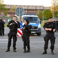 Polizeibeamte stehen auf der Straße. Hinter ihnen ist ein Einsatzwagen geparkt.