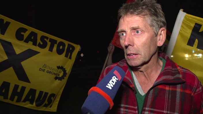 Aktivist Peter Bastian steht vor einigen Demo-Fahnen