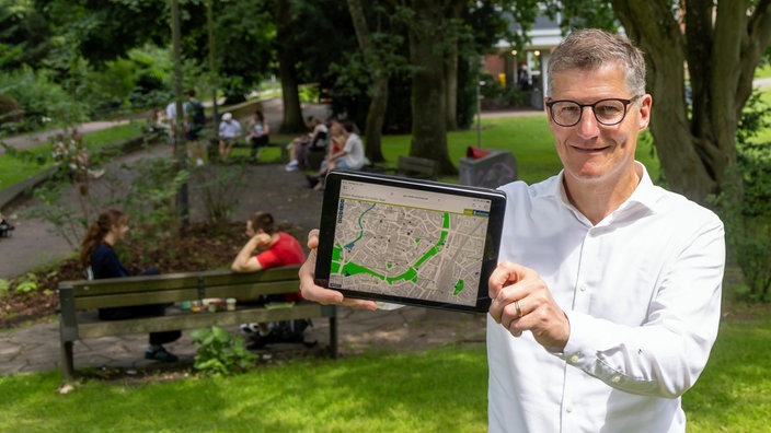 Münsters Oberbürgermeister Tilman Fuchs präsentiert per Tablet im Grünen den Coolen Stadtplan mit kühlen Orten