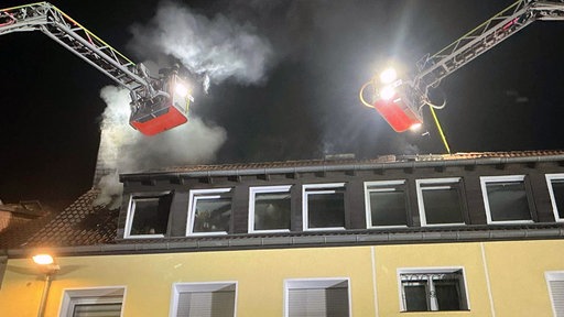 Zwei Feuerwehrkräne löschen den Brand in einem Dachstuhl.