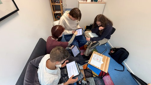 Vier Jugendliche arbeiten zusammen an Tablets.