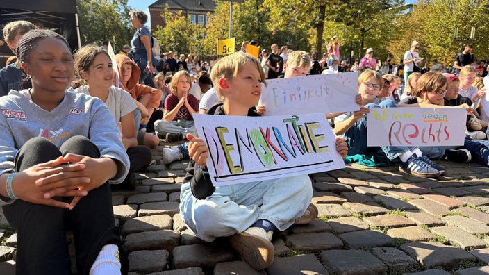Schülerinnen und Schüler halten Plakate hoch.