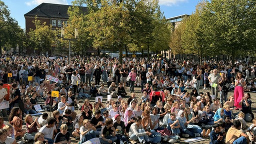 Die fünf Schulen haben sich mit allen Schülerinnen und Schülern auf dem Domplatz versammelt.