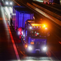 Ein LKW mit besonderem Anhänger fährt mit starker Beleuchtung auf einer nächtlichen Autobahn