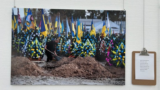Fotografie aus der Ausstellung an der Wand hängend mit Beschreibungstafel.