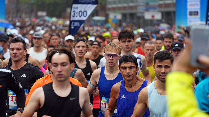Eine große Menge an Marathon-Läufern füllt das Bild. Sie schauen konzentriert auf die Strecke.