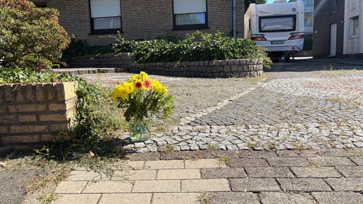 Vor dem Haus der getöteten Frau steht eine Vase mit Blumen.