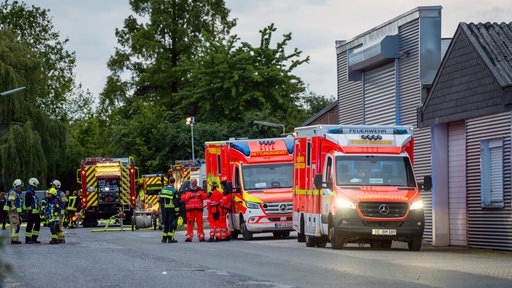 Im Morgengrauen stehen mehrere Einsatzwägen und Einsatzkräfte der Feuerwehr vor einem Haus.