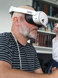 Alexander Ewen (l.) ist Glioblastom-Langzeitüberlebender. Er lässt sich von Prof. Markus Holling anhand von MRT-Bildern in der VR-Brille virtuelle Eindrücke seines Gehirns zeigen.
